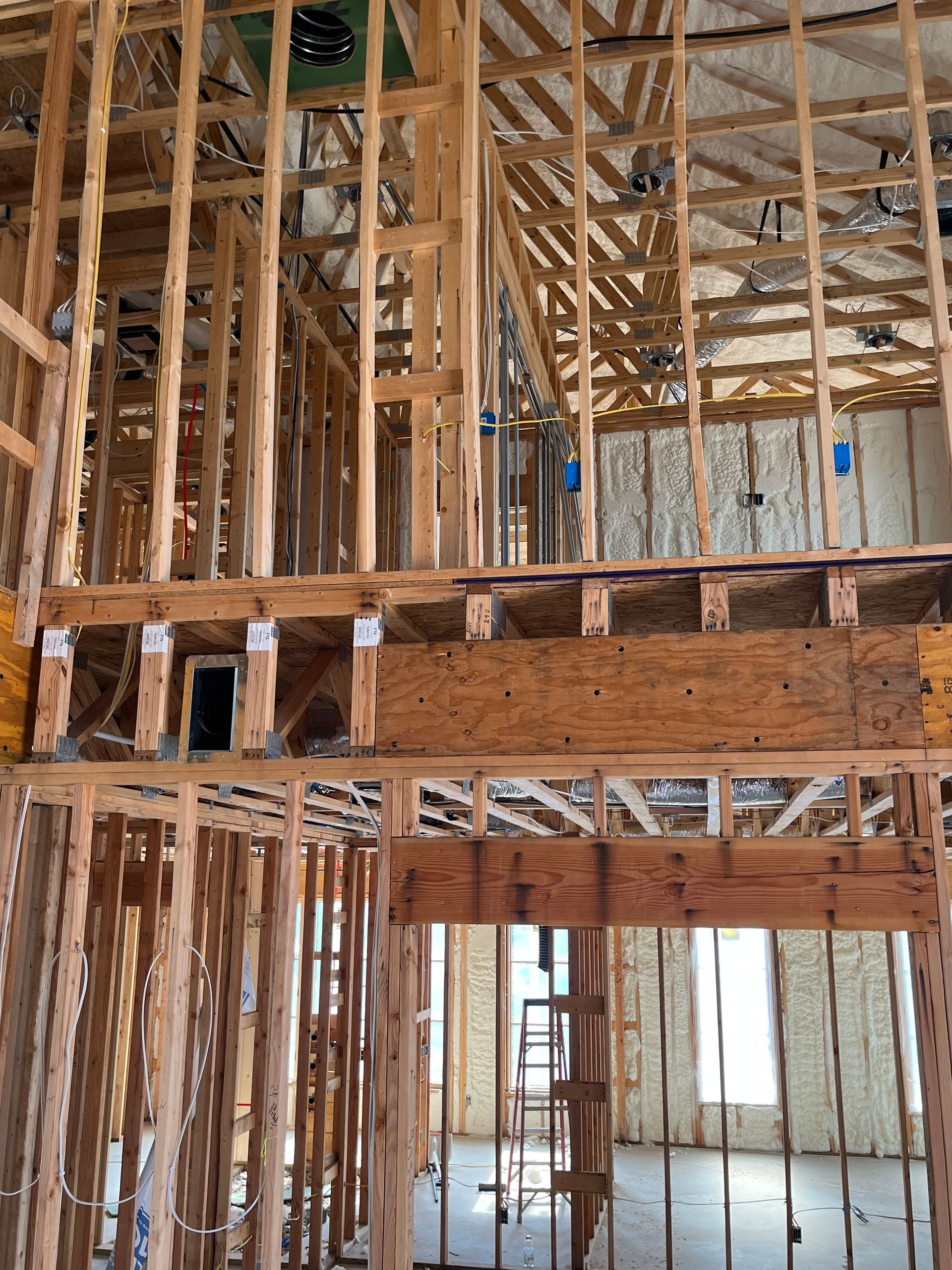 The inside of a building under construction with wooden beams and a ladder.