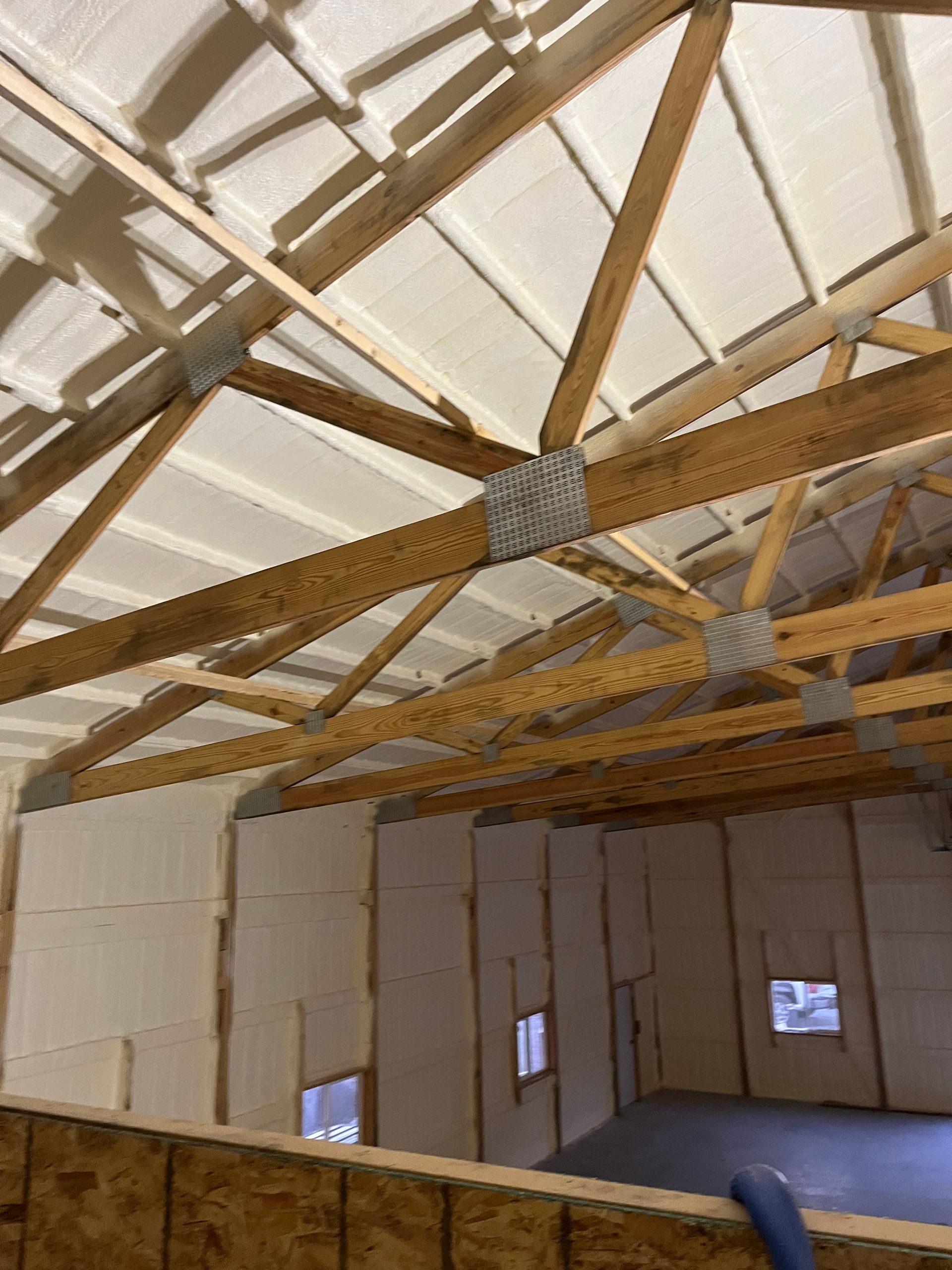 The ceiling of a building with wooden beams and insulation.